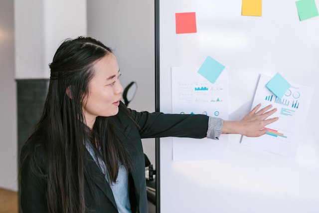 Woman Pointing At Post It Notes On A Whiteboard